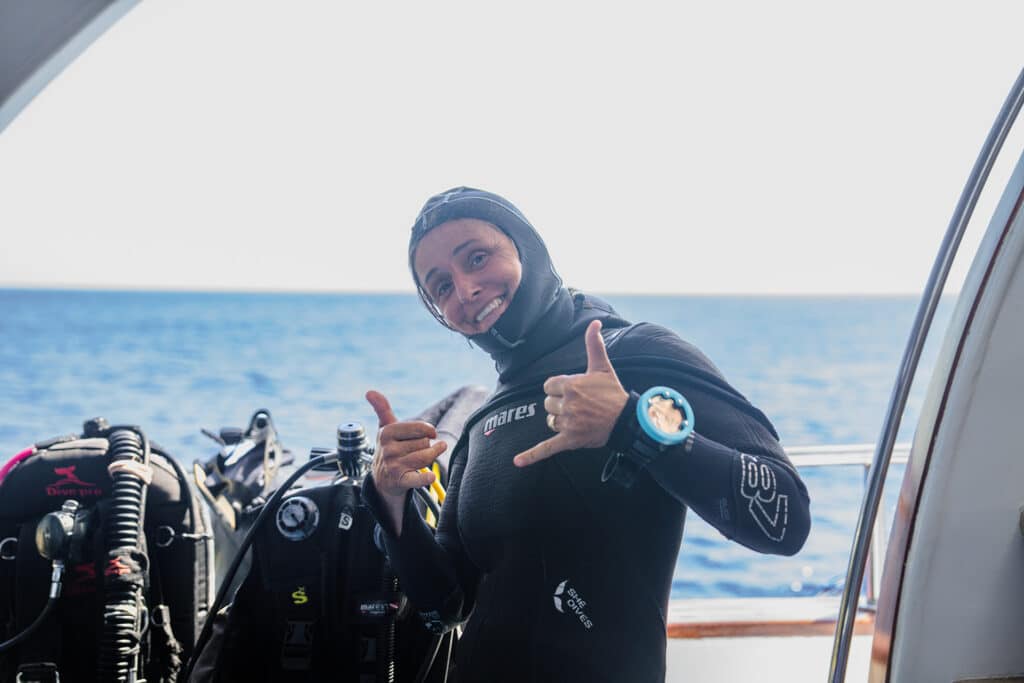 Istruttrice del Camel Dive Club pronta per un'immersione invernale nel Mar Rosso Istruttrice del Camel Dive Club con muta e cappuccio sulla barca, pronta per un'immersione invernale nel Mar Rosso