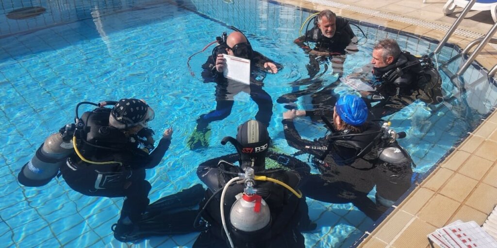 dive-instructor-course-2023 Divers kneeling in a circle with their instructor during a pool session at Camel Dive Club