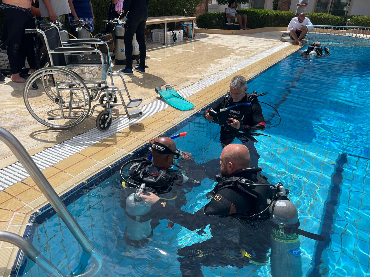 SSI Certified Diver Course - Wheelchair by the pool with instructors and divers training in the dive pool